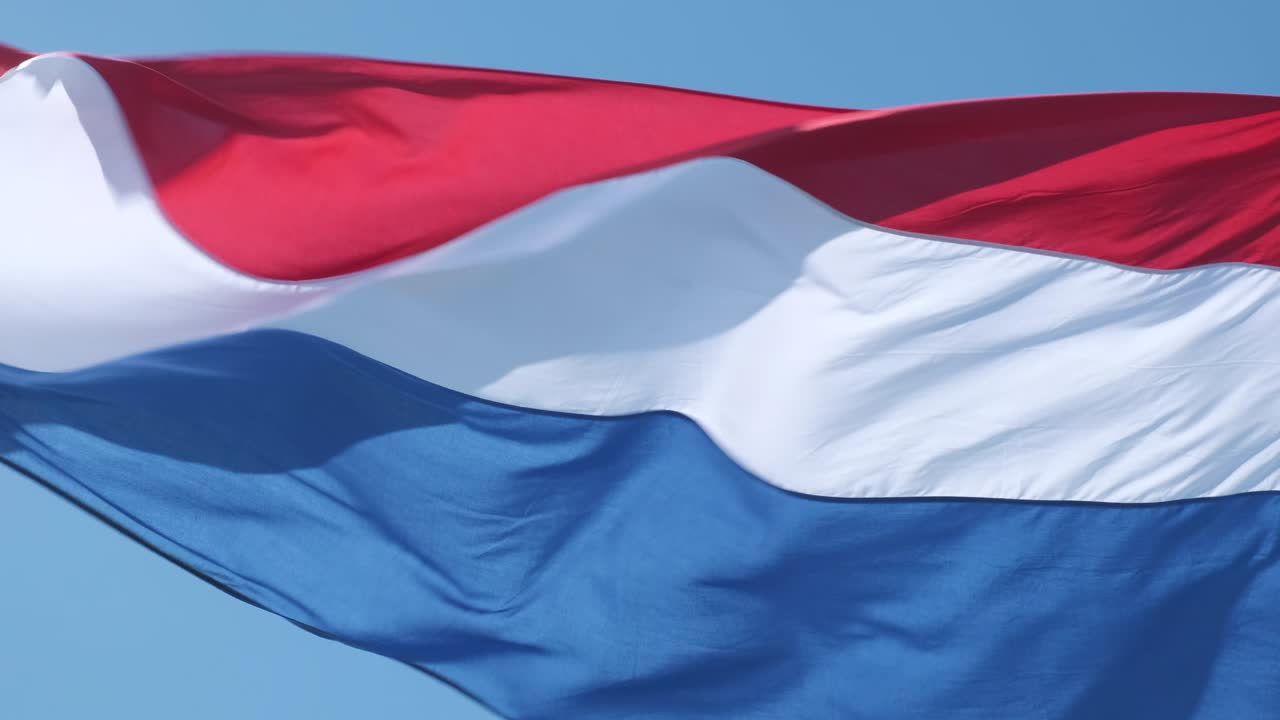 네덜란드의 빨간색, 색 및 파란색 발이 은 날 배경에 파란 하늘과 함께 바람에 흔들리고 있습니다.