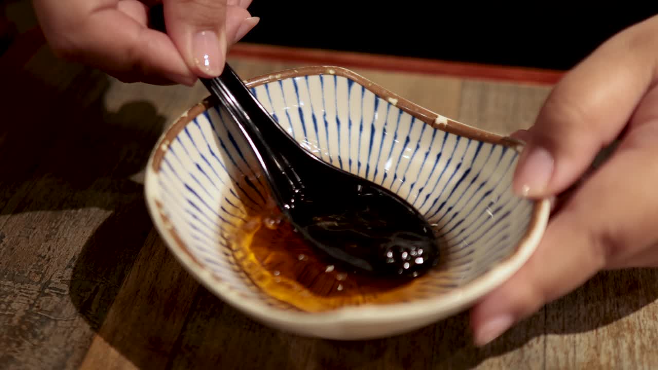 Hands stirring sauce with a black spoon