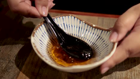 hands stirring sauce with a black spoon