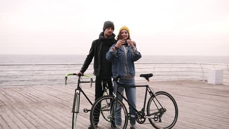 Happy-Young-Couple-Taking-Selfie-By-Mobile-Phone-Near-The-Seaside-In-Cloudy-Day-1