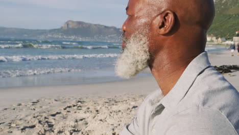 senior african american man sitting at the beach, admiring the view