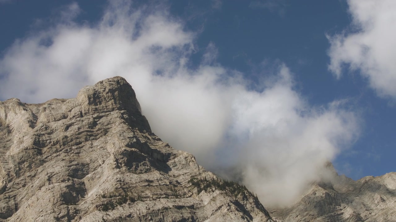 Passando accanto alle alte vette delle Montagne Rocciose coperte da nuvole
