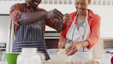 Video-of-happy-african-american-couple-baking-together-in-kitchen