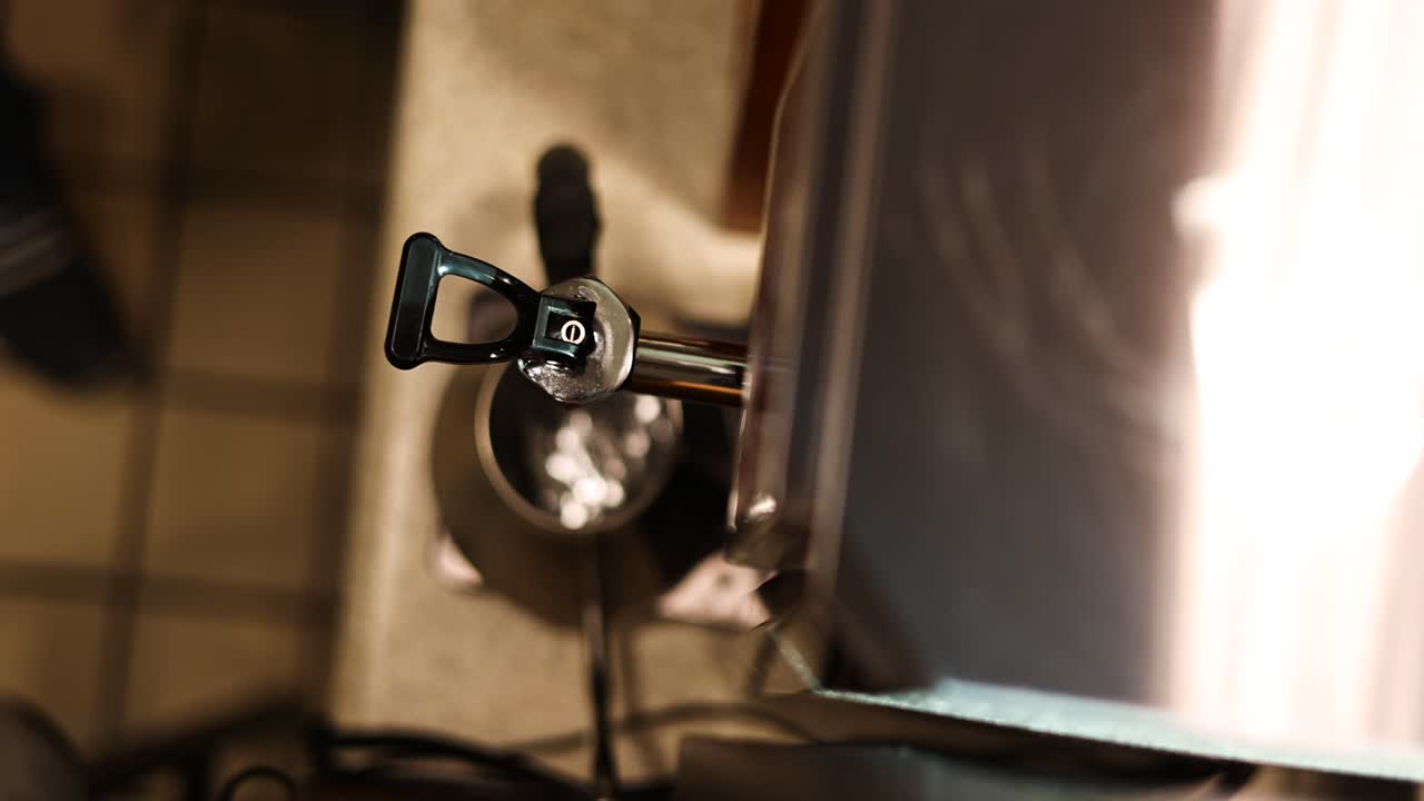 Vista statica dall'alto di un barista che posiziona un bricco sotto il beccuccio dell'acqua di una macchina da caffè espresso e lo riempie con acqua calda — bricco pulito in acciaio inossidabile, riprese B-roll fluide dall'alto di preparazione in caffetteria.