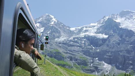 scenic train ride in the valley of alps mountain window with a man looking from the window, lauterbrunnen switzerland