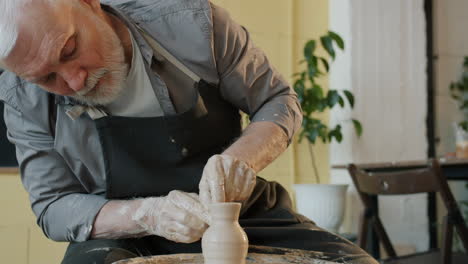 senior pottery artist shaping clay on wheel