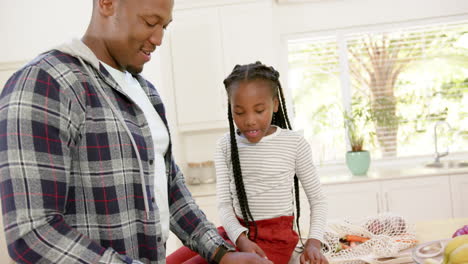 Felices-Padres-Afroamericanos-E-Hija-Desempacando-Bolsas-De-Compras-En-Casa,-Cámara-Lenta