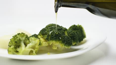 Slow-motion-shot-of-Olive-oil-poured-on-top-of-Boiled-broccoli-plate,-Close-up