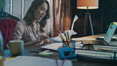 mujer de negocios feliz analizando datos financieros en su computadora portátil.