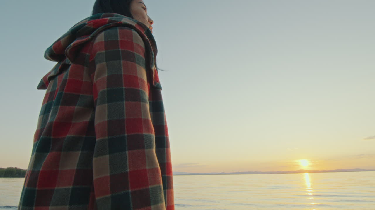 그림 같은 해가 지는 것을 지켜보며 등불을 들고 호수 에 서 있는 젊은 여성