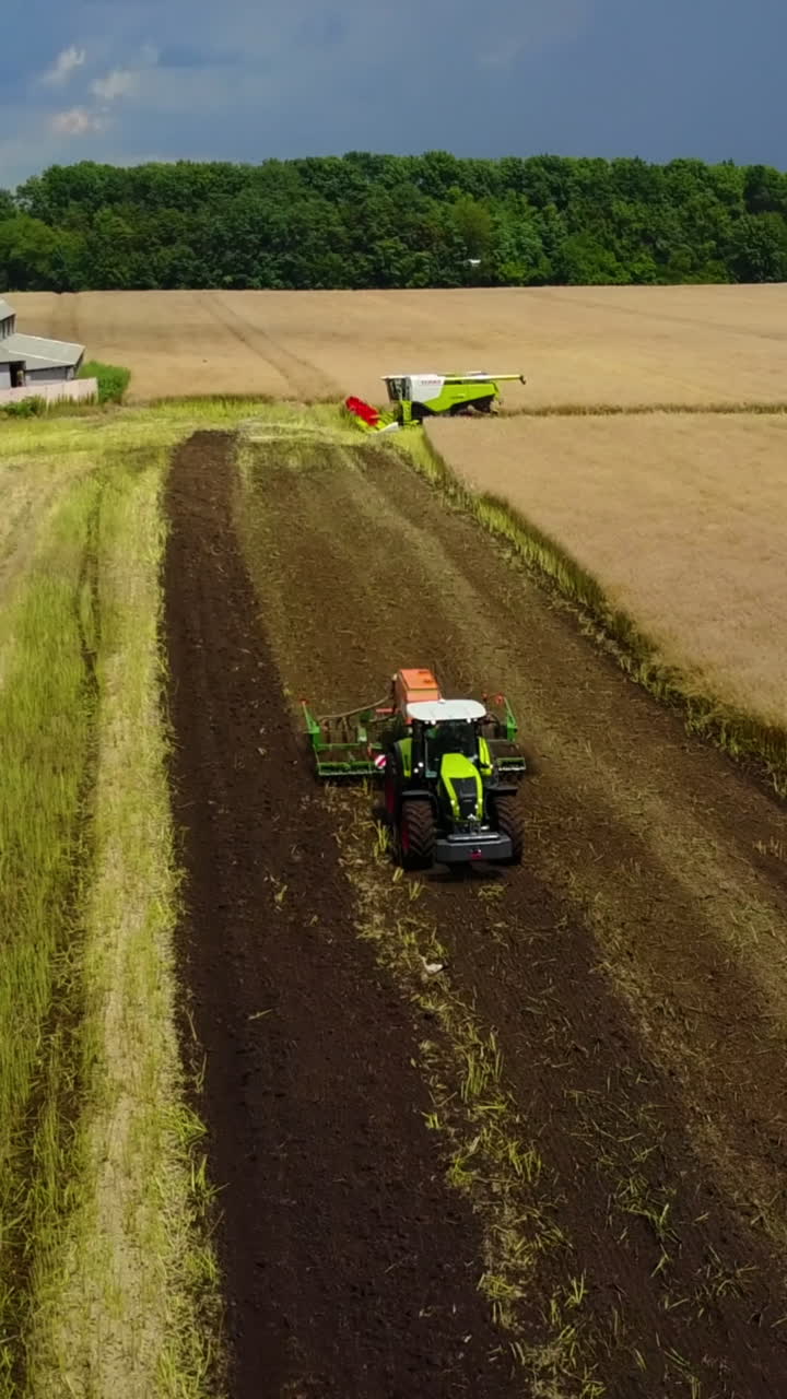 Green Tractor Working In A Field. Aerial shot of the green tractor working in a field or farmland Vertical video