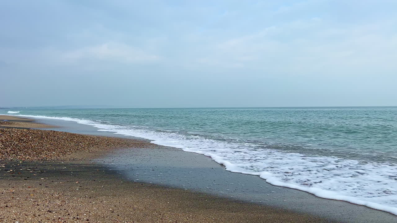 寧靜沿海地區的破曉時分，海浪輕柔拍打著近岸的沙灘。