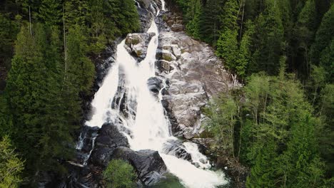 slow pullback aerial shot of silver falls waterfall in a forest in deep cove, vancouver, canada