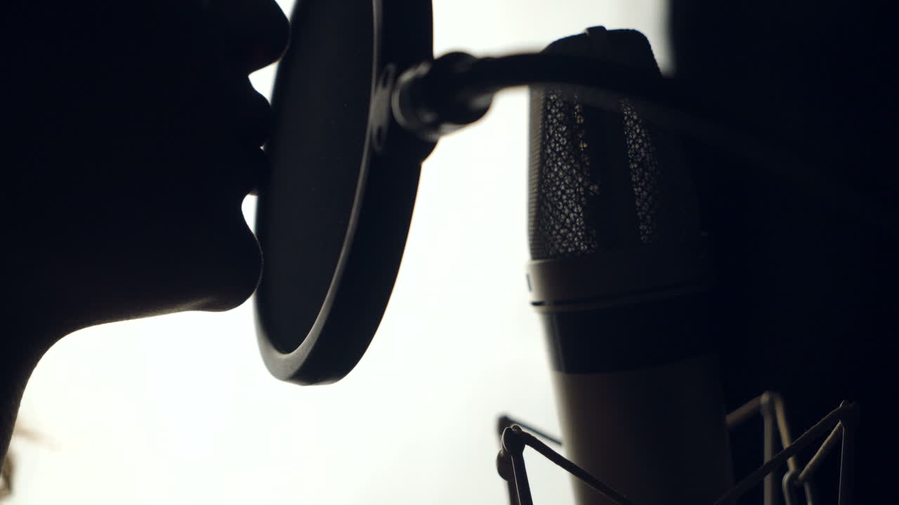 woman is recording a song in an audio studio. The silhouette of a woman's face is singing a song on the white background. Close-up
