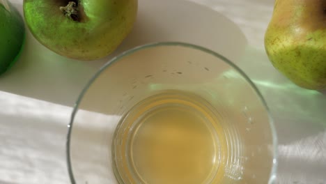 freshly poured natural cider in a glass surrounded by apples