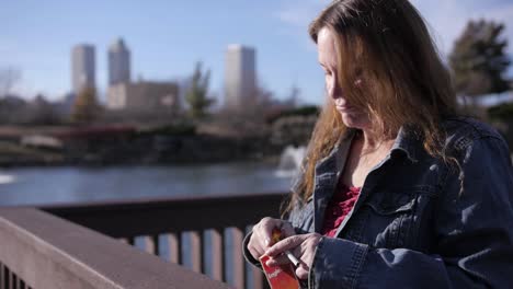 Tired,-homeless-woman-looking-out-over-the-water-putting-away-her-cigarette-pack