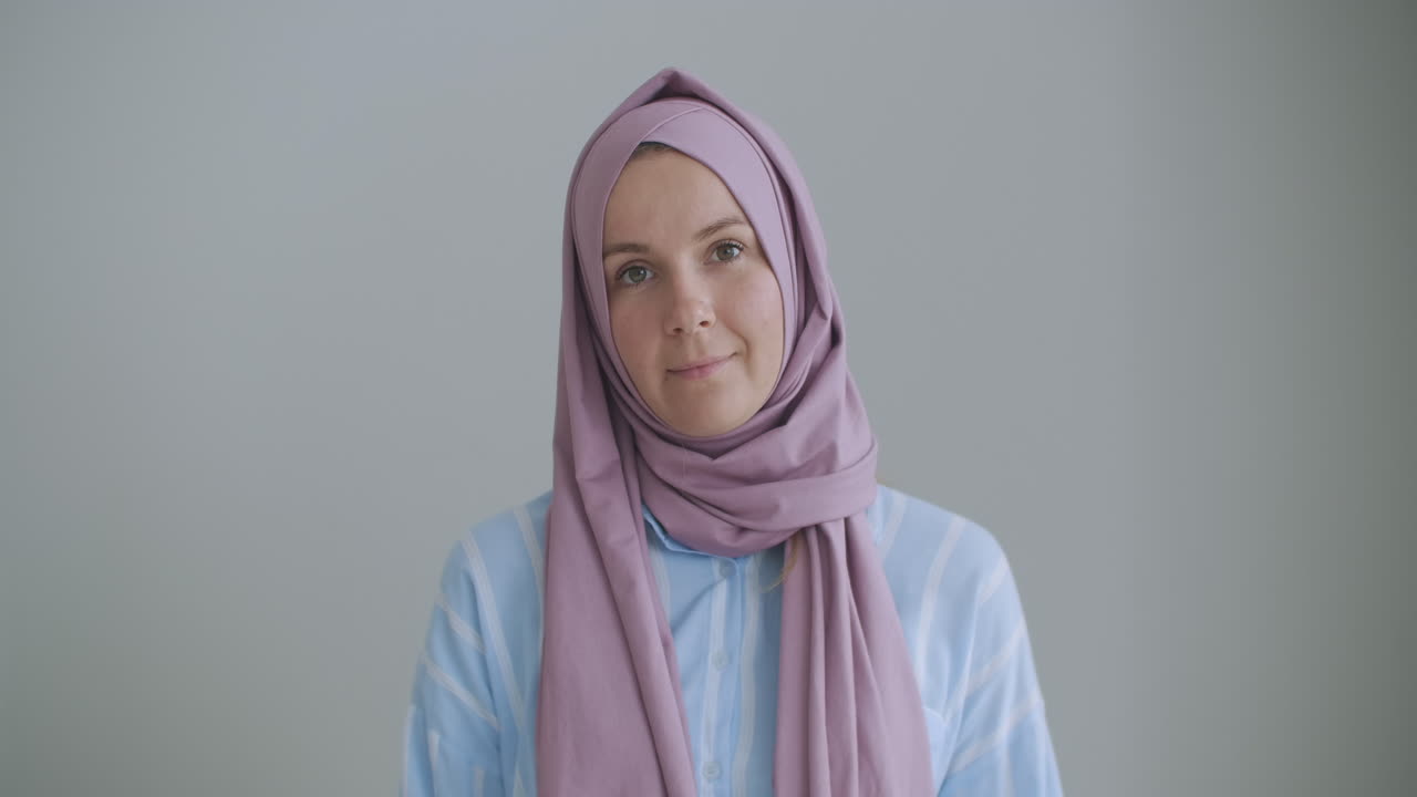 카메라를 바라보고 머리를 끄덕이는 히자브를 입은 무슬림 여성이 비디오 링크를 통해 이야기하고 강의를 듣고 있습니다. 원격 비디오 대화