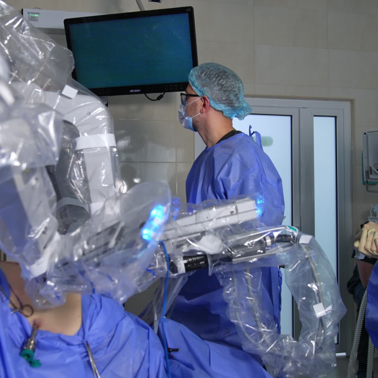 Two doctors look at the screen displaying the surgery procedure. Da Vinci robot performs surgery on patient's abdomen