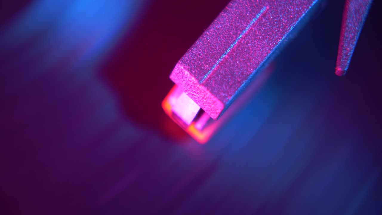 Primo piano di un oggetto metallico luminoso con colori pulsanti.