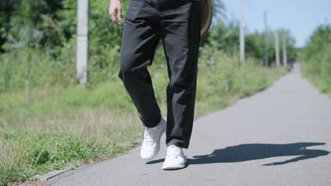 young man walking with guitar on street near forest