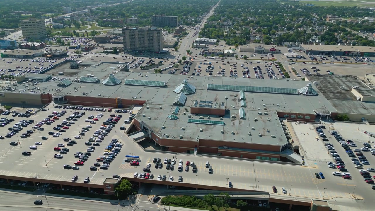 Imagem aérea de drone em ângulo alto em panorâmica sobre o Polo Park e os empreendimentos comerciais circundantes em um dia de verão ensolarado em Winnipeg.