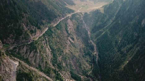 vertical panning up drone shot while drone flying backwards, of a mountain road next to a cliff