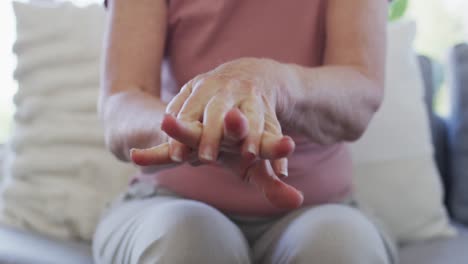 mid section of senior woman sanitizing her hands at home