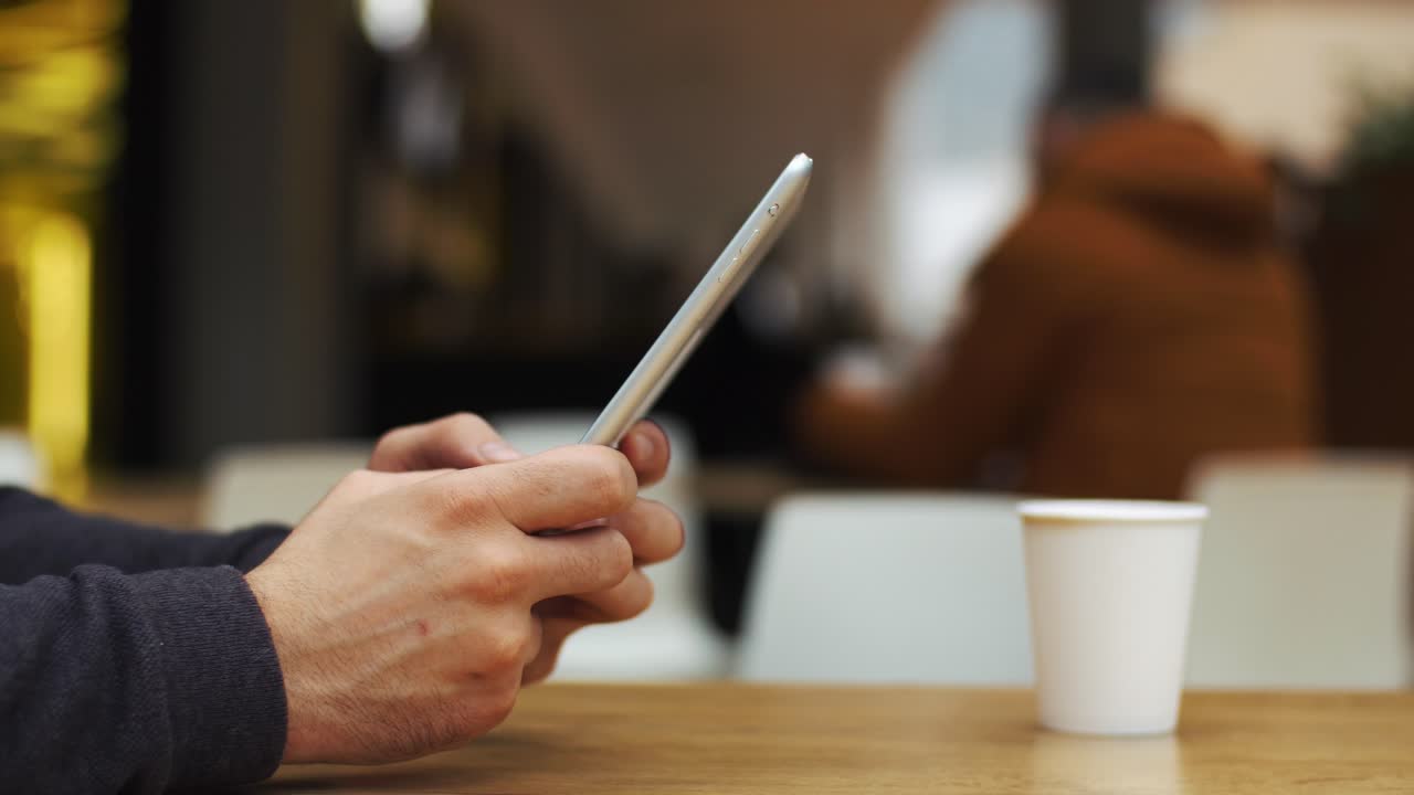 Hands using a tablet at a table