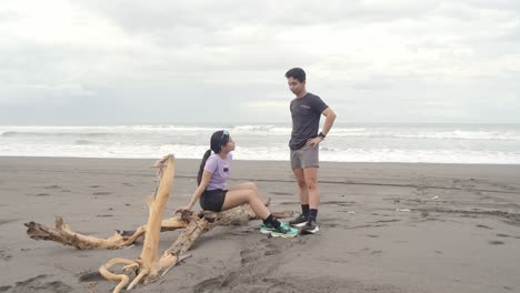 couple talking on a beach with driftwood