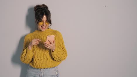 woman using phone in yellow sweater