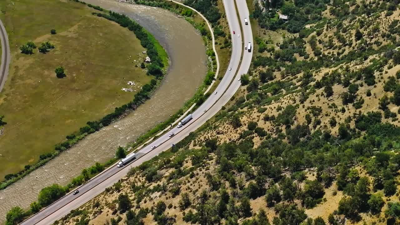 Strada che curva lungo il fiume con colline in Colorado