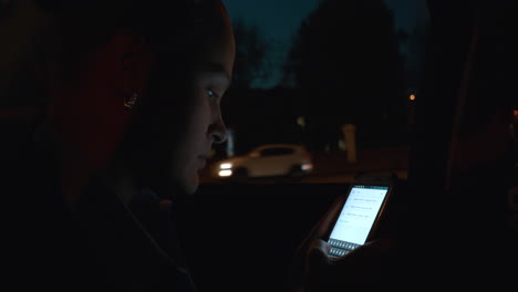 woman with smart phone in car at night