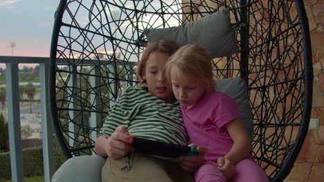 siblings playing console on balcony