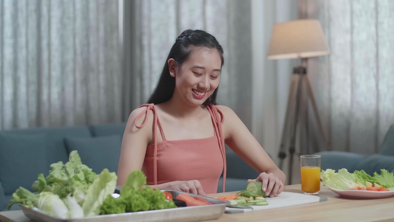 웃는 아시아 여성이 칼을 들고 집에서 카메라에 엄지손가락을 보여주기 전에 호박을 잘라