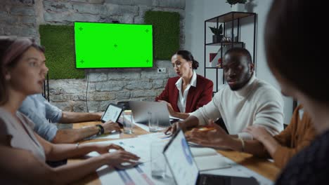 equipo multiétnico diverso de empresarios profesionales que se reúnen en la moderna sala de conferencias de la oficina con pantalla clave de croma verde presentación de televisión equipo creativo discutir, negociar, planificar la estrategia