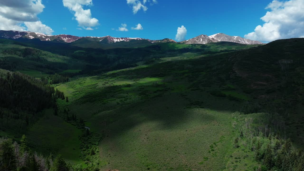 Old mount Snowmass Aspen Wilderness aerial drone view early summer June July Mt Sopris Rocky Mountains peaks farm open space landscape sunny blue sky Capital Peak Maroon Bells National Forest backward