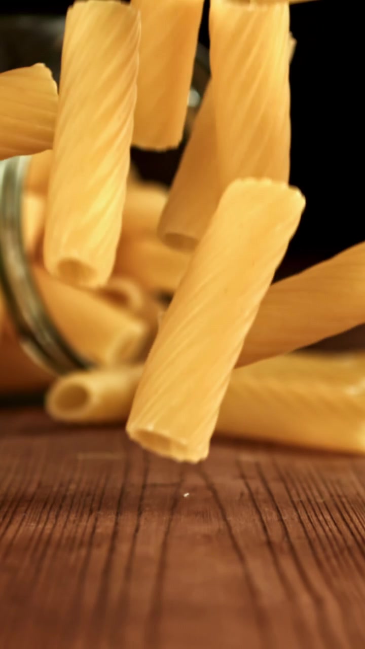 Rallentatore di pasta Rigatoni secca che cade su un tavolo di legno