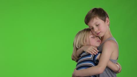 el hermano mayor consuela a su hermano menor frente a la pantalla verde