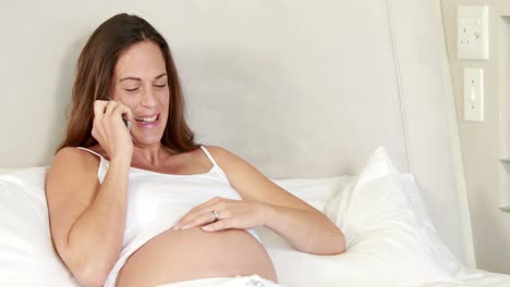 Pregnant-woman-relaxing-on-bed-talking-on-phone