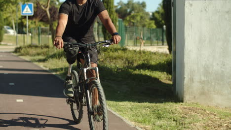 long shot of focused man with artificial leg riding bike in park