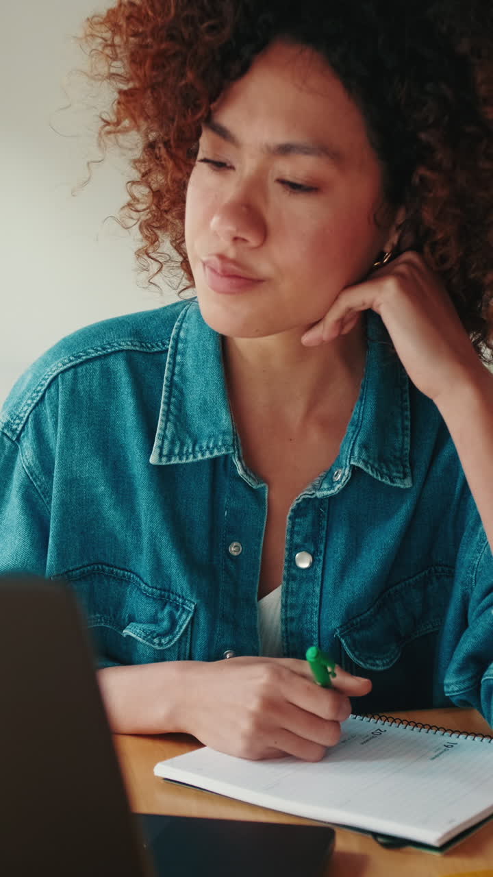 Jovem Mulher Escrevendo em Caderno e Sorrindo Durante Chamada de Vídeo