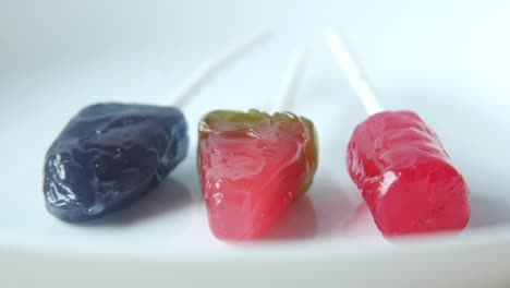 three colorful lollipops on a white plate