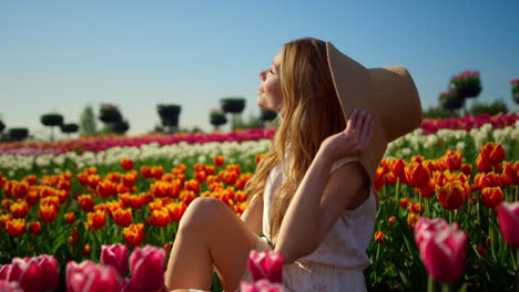 fancy woman enjoying sun in tulip field. relaxed girl turning face to sun.