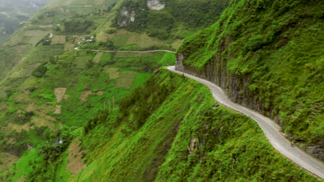 fast left aerial pan of a scenic road cut into the mountains of the gorgeous ma pi leng pass in northern vietnam