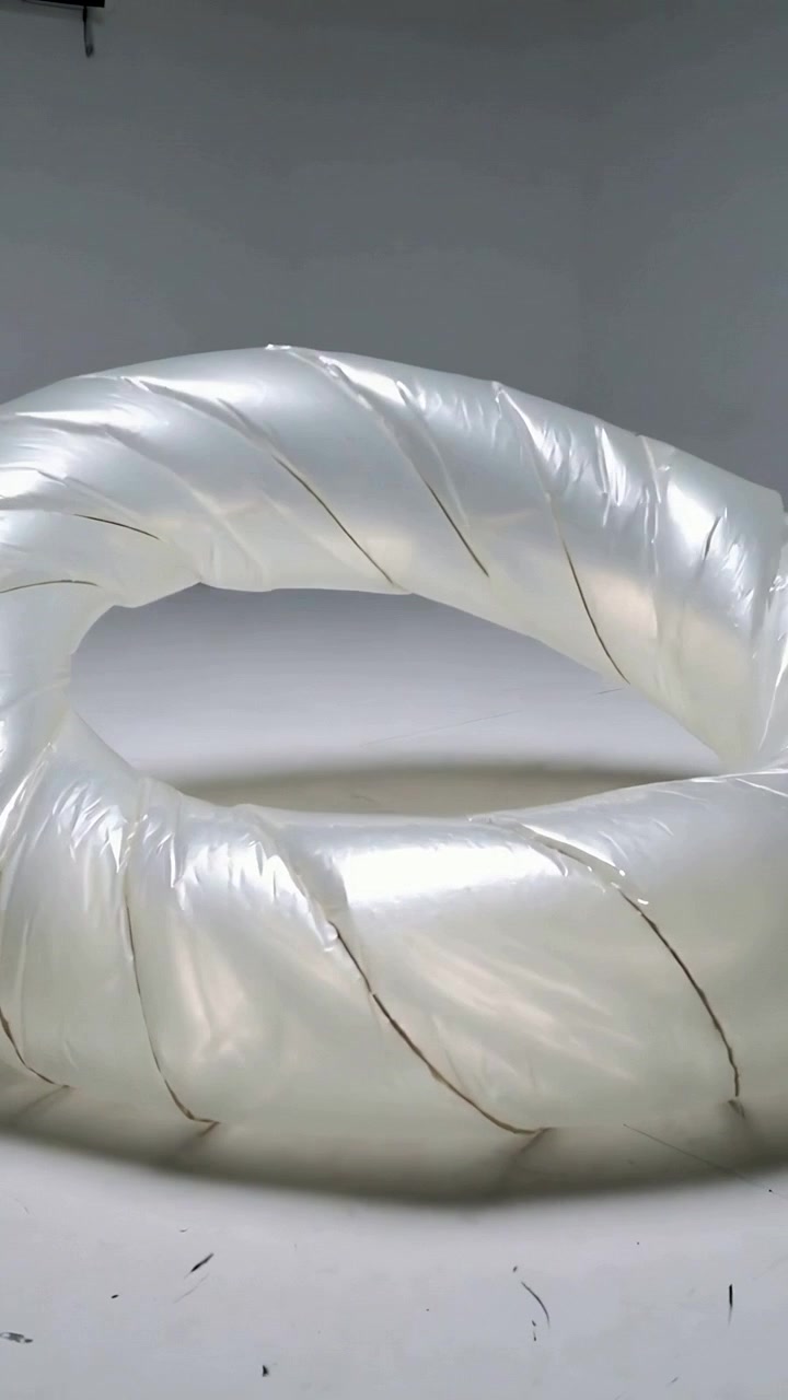 Vertical video: Rising camera, inflatable ring rotating to reveal inner hole on white cyclorama