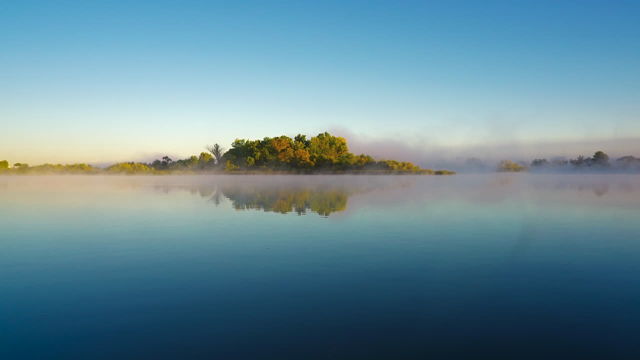 Misty Over The Calm River With Reflection Of Trees And Blue Sky. - wide static shot