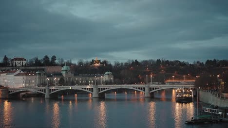 manes bridge in prague: serene river view with cityscape and bridge silhouette