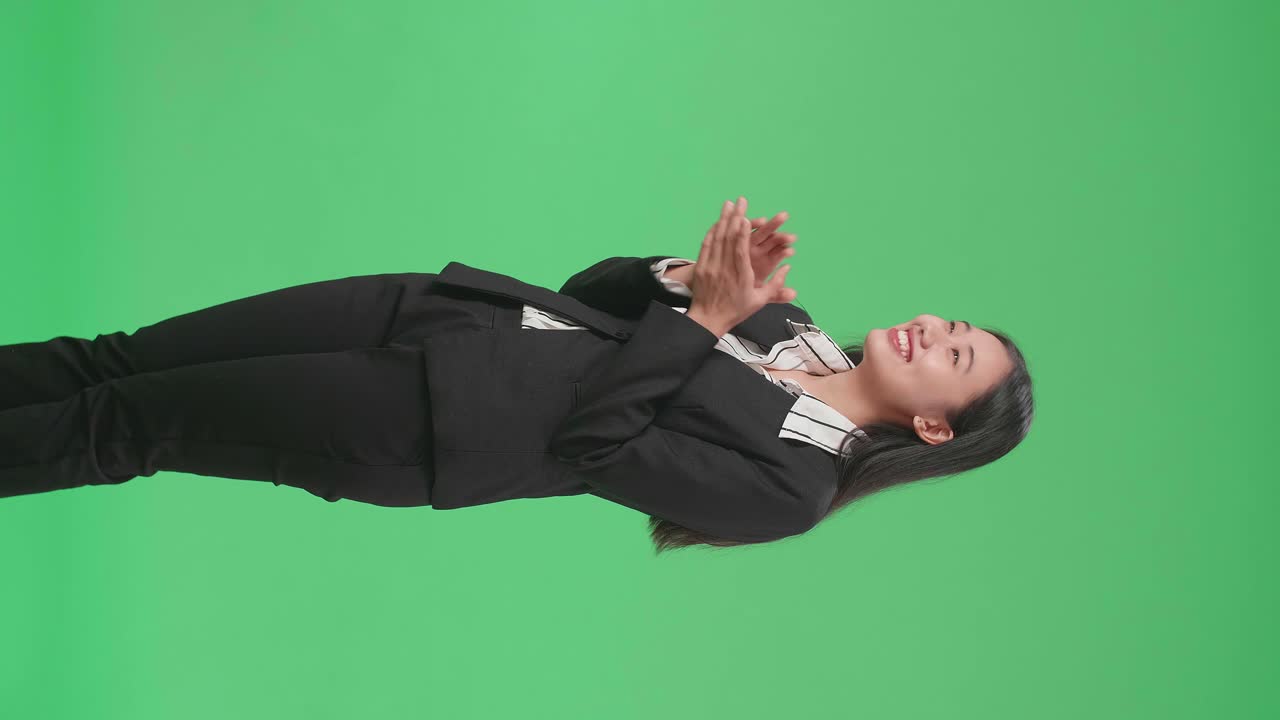 Side View Of An Asian Business Woman Clapping Her Hands In The Green Screen Studio