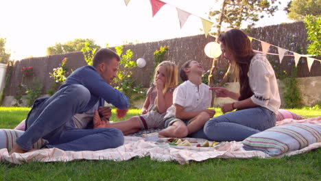 family enjoying picnic on blanket in garden