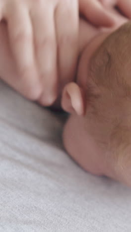 skilled pediatrician massages actively back and shoulder blades of newborn boy lying on stomach extreme close view